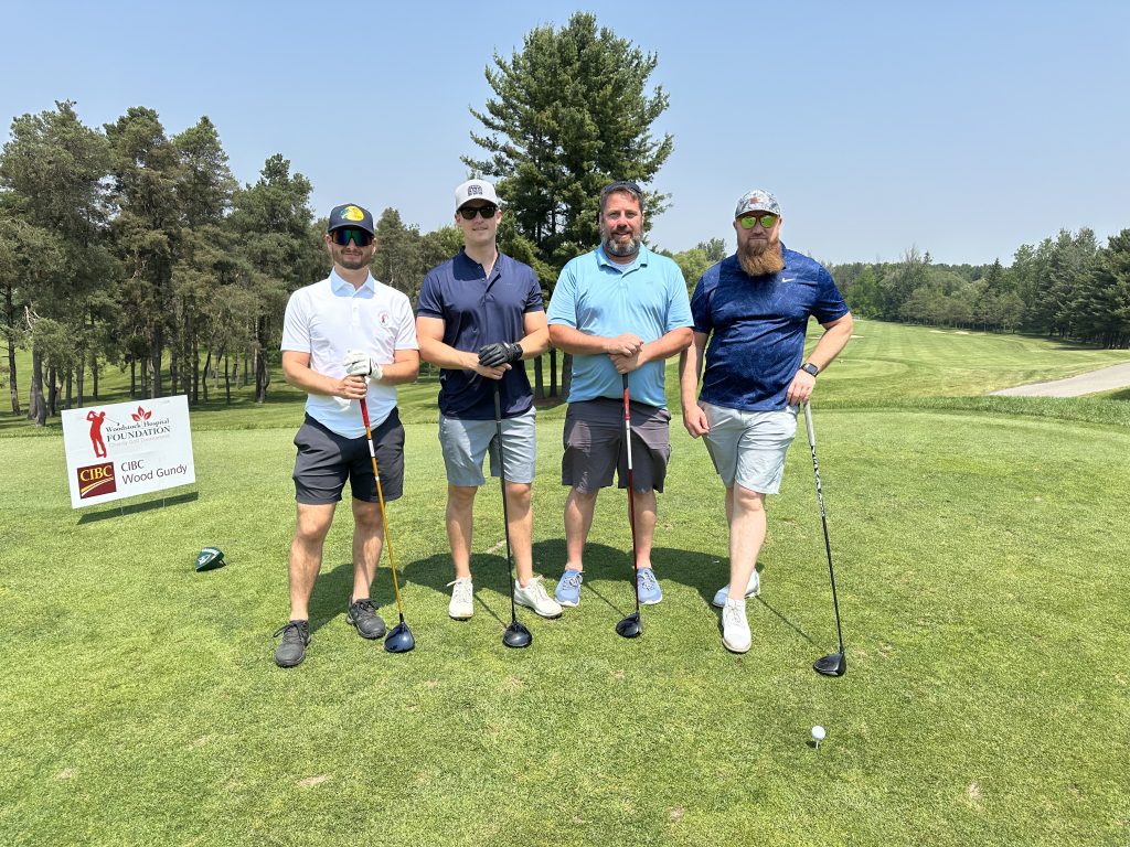 photo of four golfers standing with golf clubs on the golf course