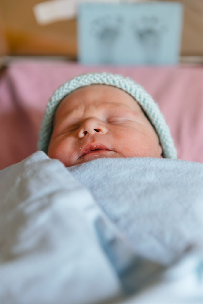 newborn baby wrapped in a blue blanket and in a blue hat