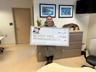 Kaitlyn standing holding her cheque in our office